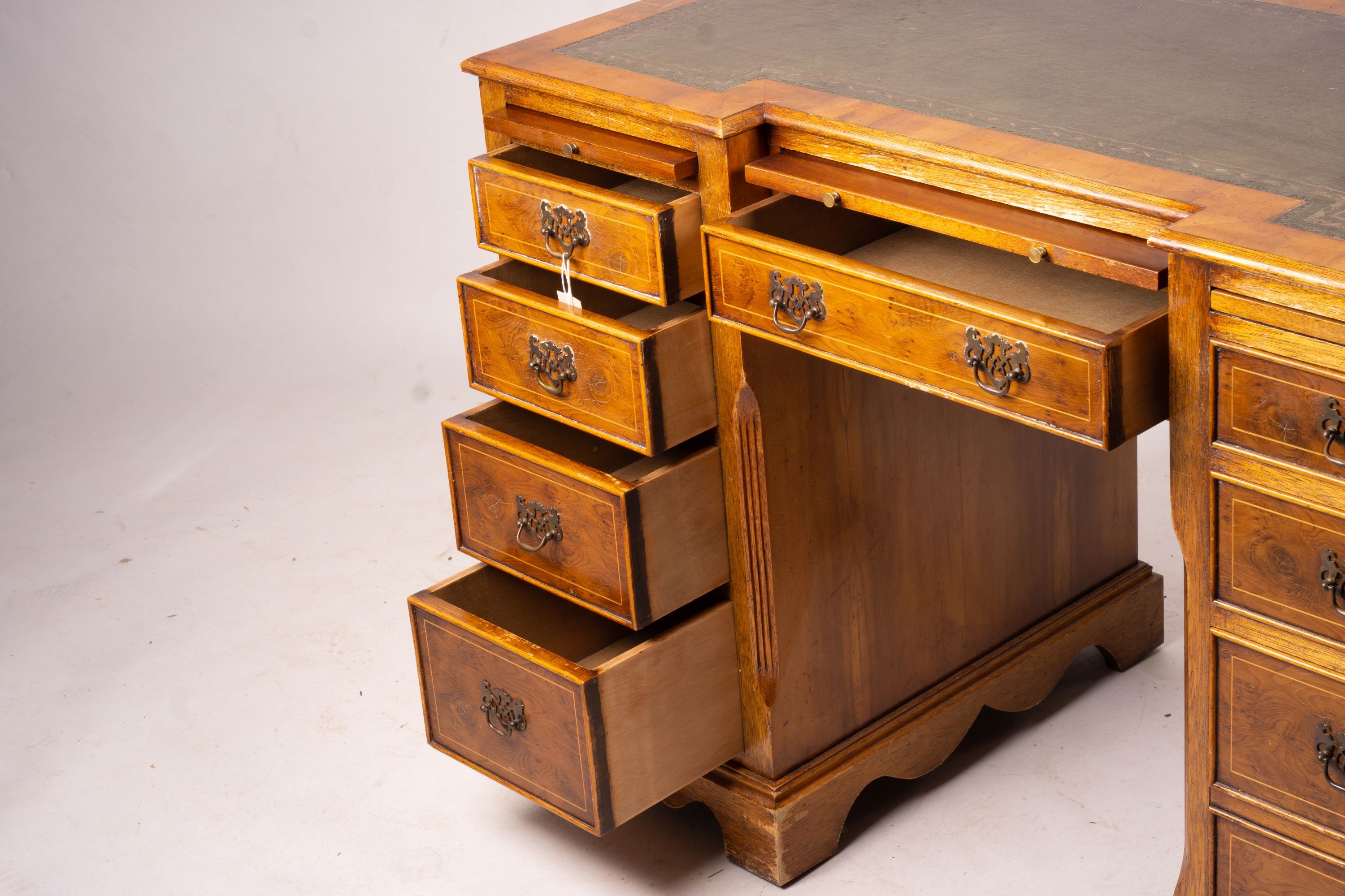 A reproduction yew inverse breakfront kneehole pedestal desk fitted green skiver, width 114cm, depth 58cm, height 77cm